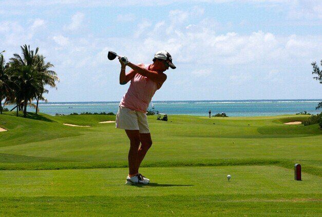 Golfer mid-swing on coastal course